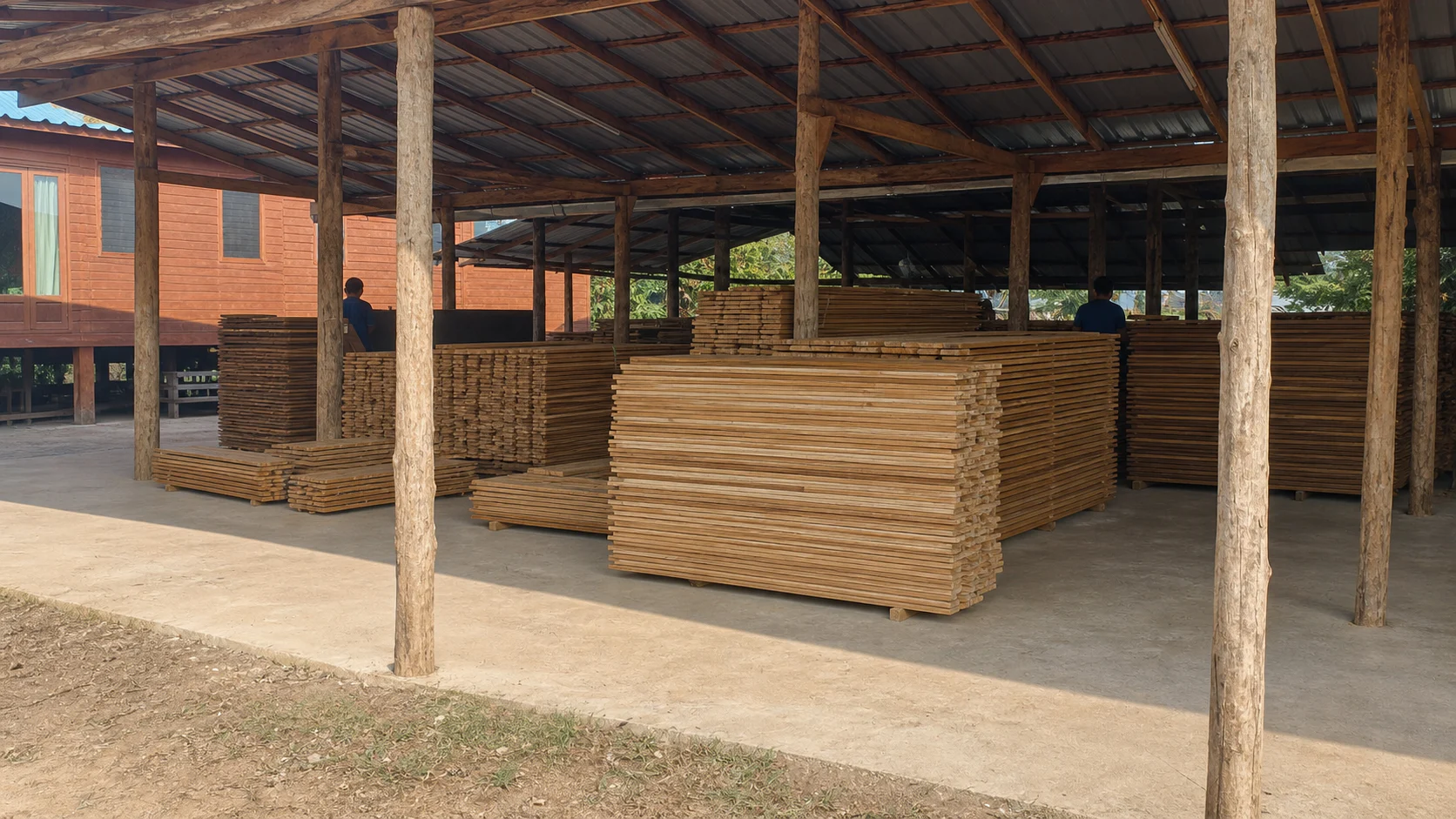 Open-sided Thai timber workshop with large organised stacks of teak boards